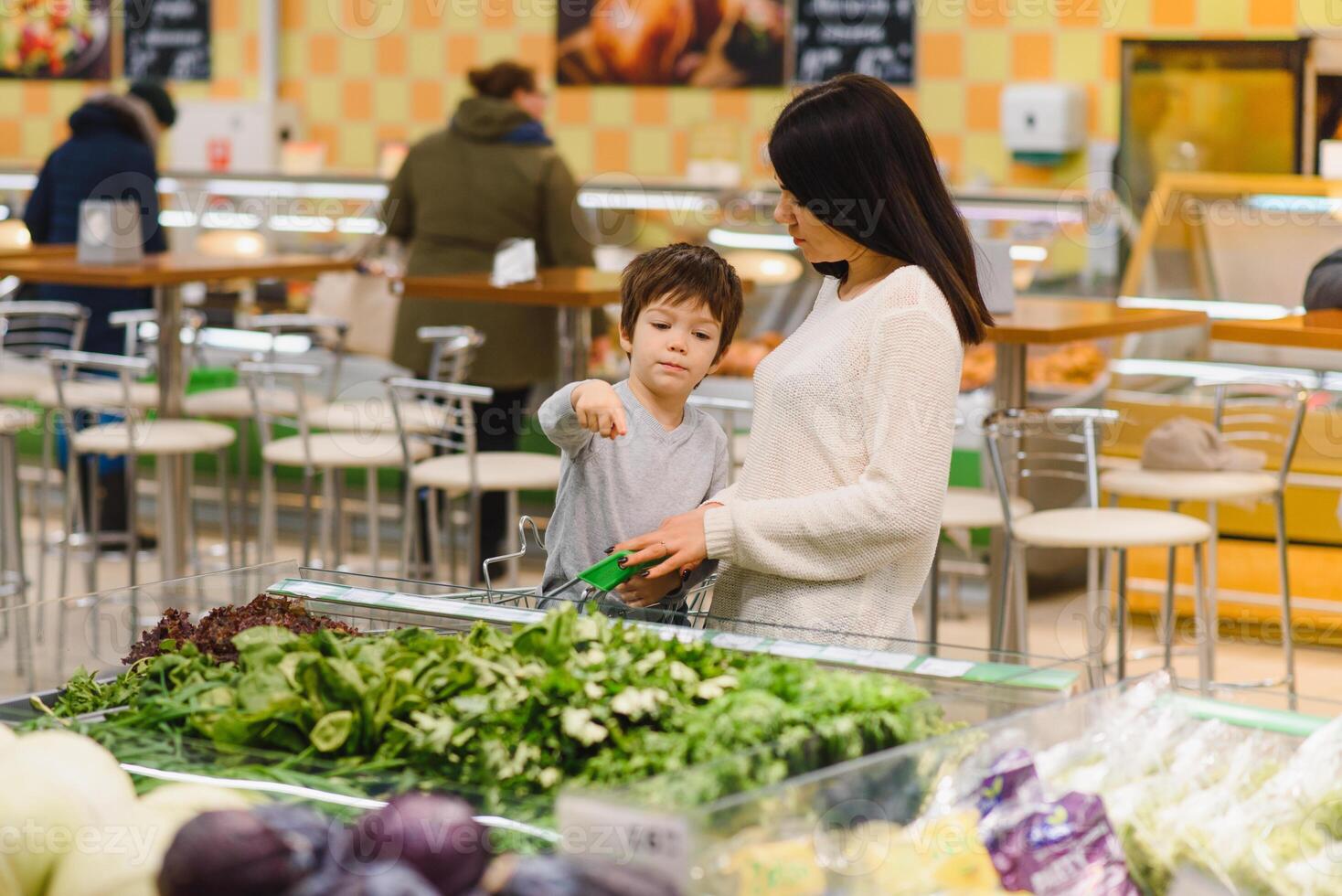 giovane madre con sua poco bambino ragazzo a il supermercato. salutare mangiare concetto foto