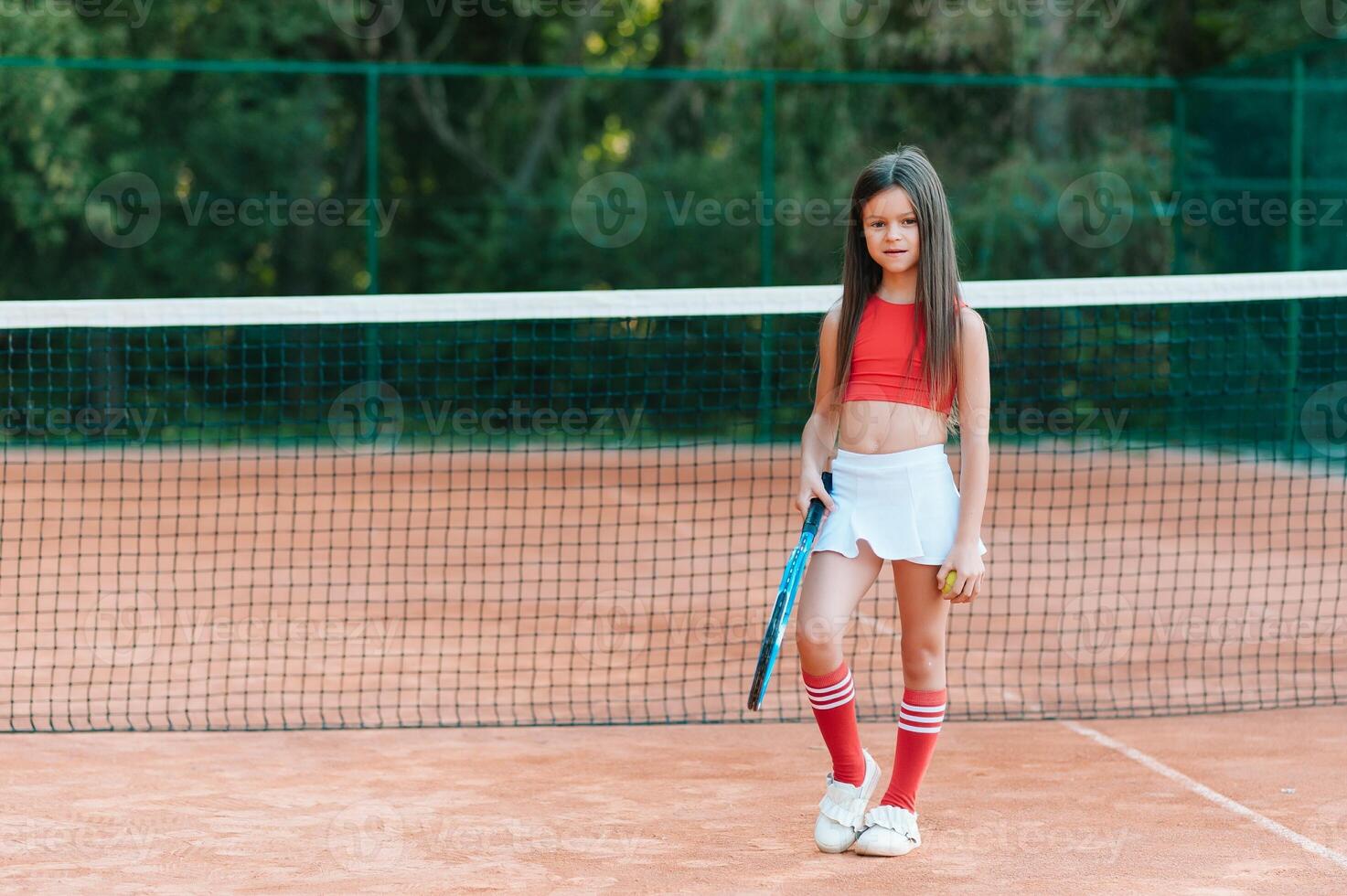 bambino giocando tennis su all'aperto Tribunale. poco ragazza con tennis racchetta e palla nel sport club. attivo esercizio per bambini. estate attività per bambini. formazione per giovane ragazzo. bambino apprendimento per giocare foto