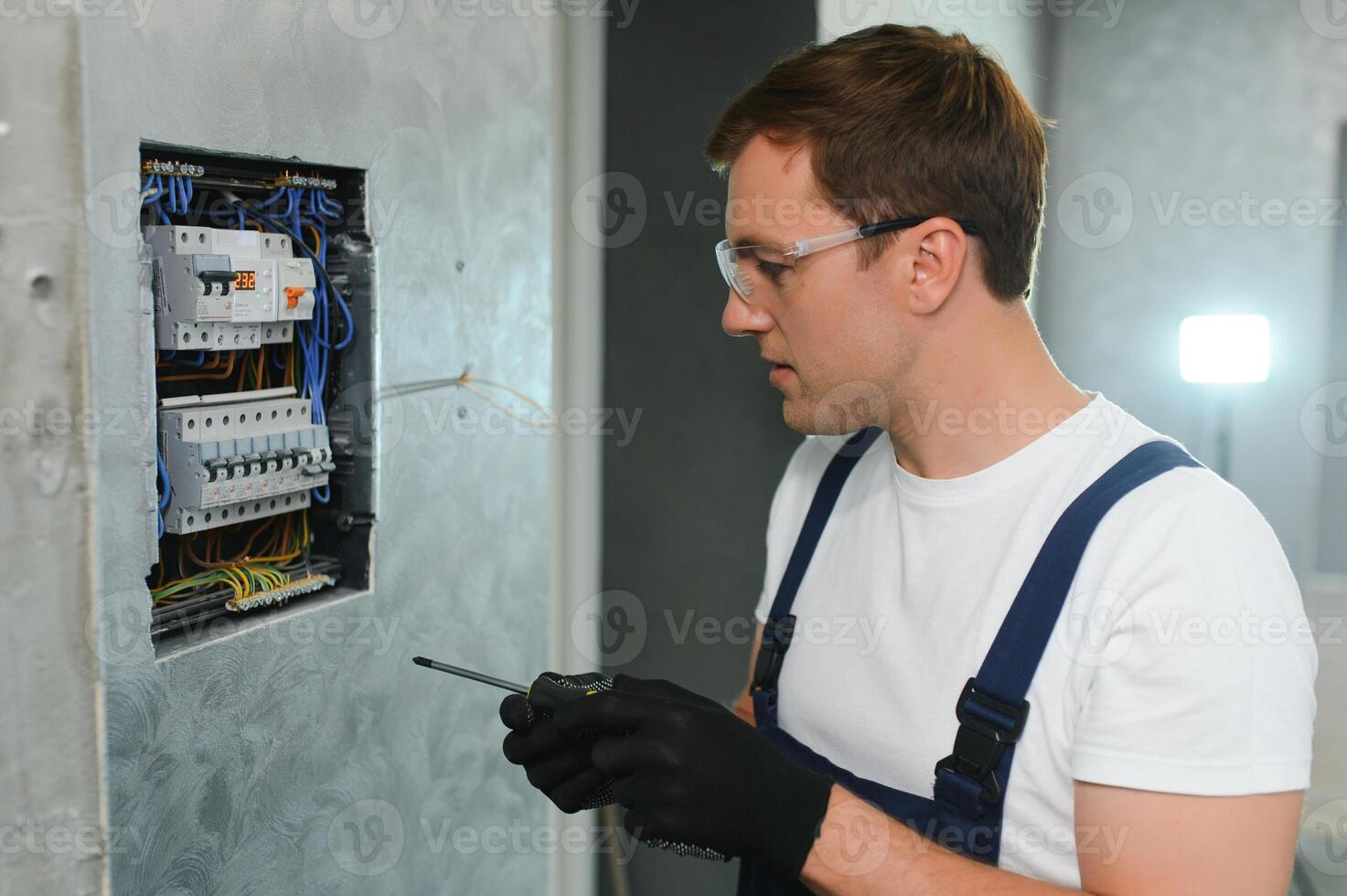 elettricista lavoratore a opera su un elettrico pannello foto