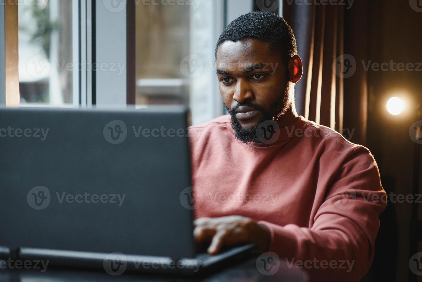 africano americano uomo Lavorando su il computer portatile nel un' bar. foto