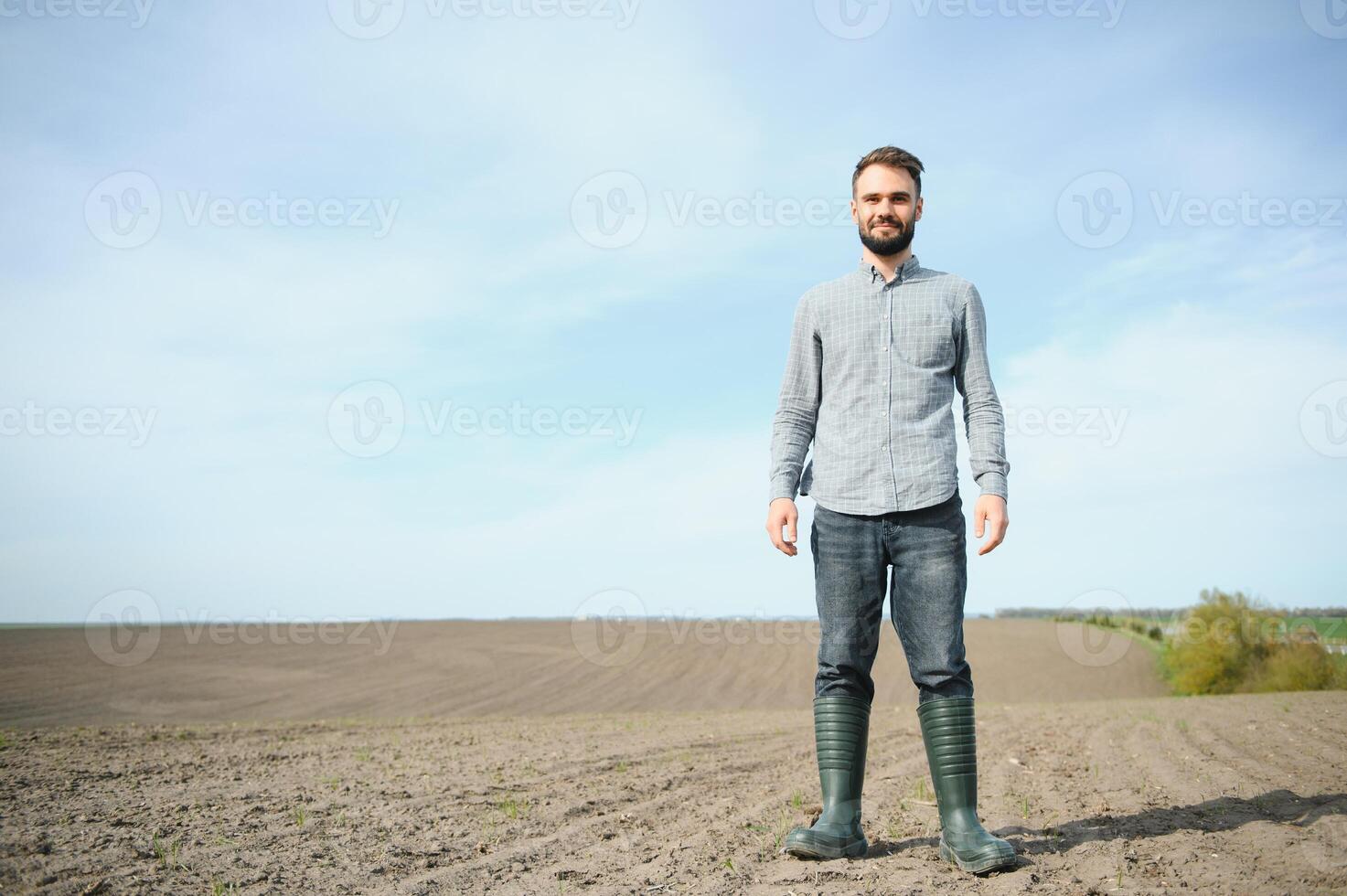 un' contadino nel stivali lavori nel un' campo seminato nel primavera. un agronomo passeggiate il terra, valutare un' arato campo nel autunno. agricoltura. foto