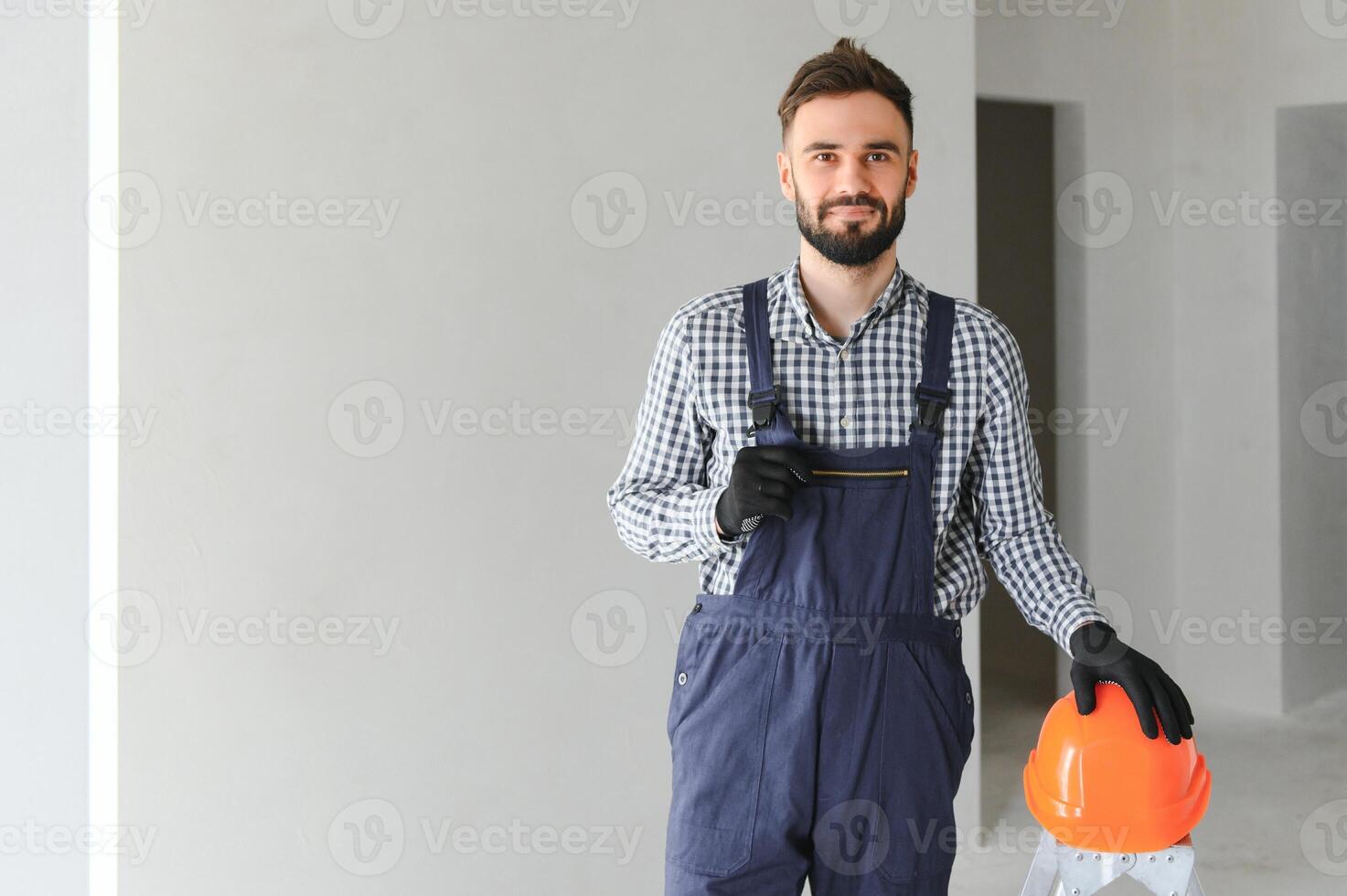 ritratto di bello meccanico con stoppie nel blu complessivamente, camicia avendo il suo braccia attraversato, guardare a telecamera foto