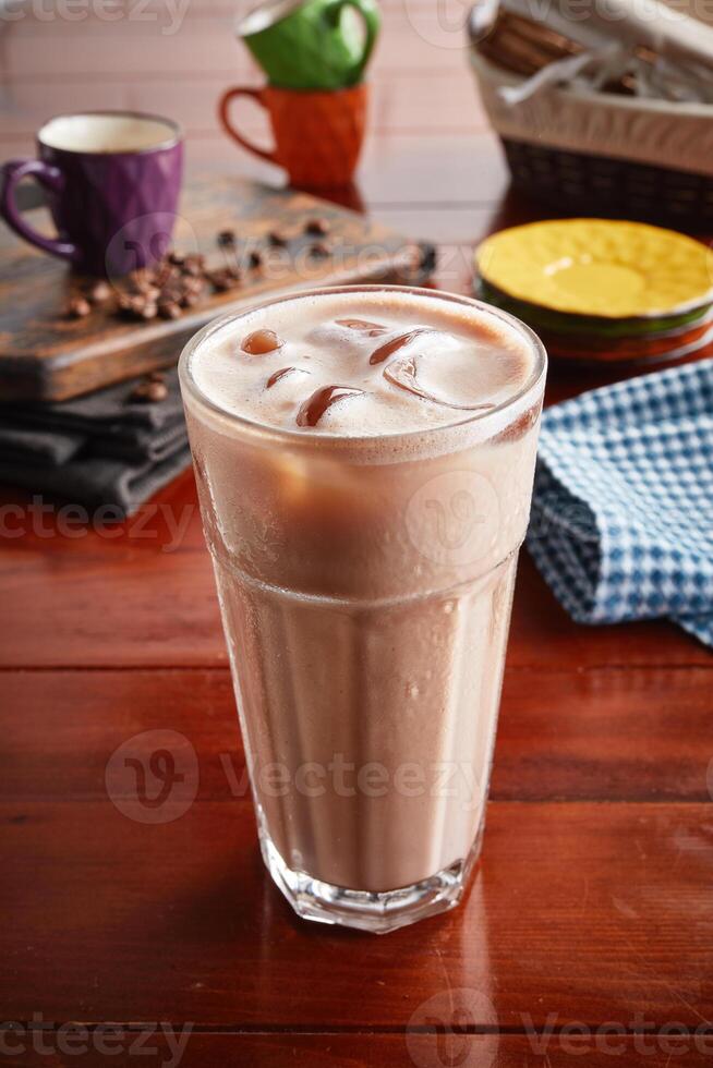 un' bicchiere di salutare fresco ghiacciato latte macchiato isolato su di legno sfondo lato Visualizza foto