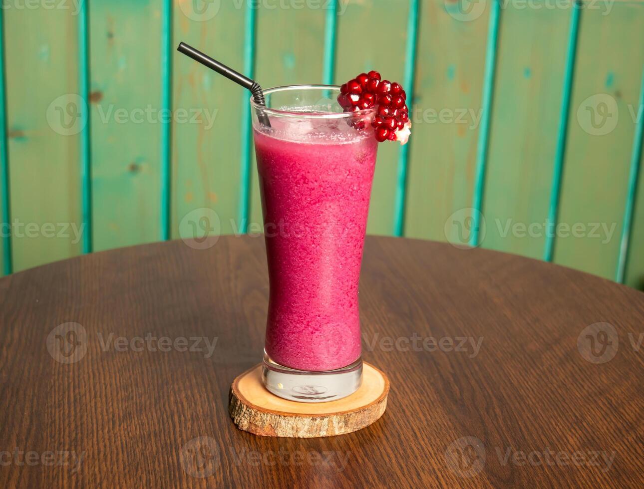 un' bicchiere di Melograno succo con Melograno frutta e cannuccia isolato su buio di legno tavolo, pieno di vitamine salutare bevanda foto