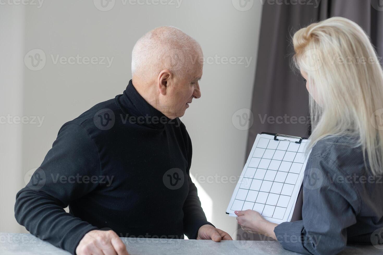 vicino su di sorridente giovane caucasico femmina terapista o gp avere consultazione con vecchio maschio paziente nel clinica o Ospedale. contento donna medico parlare consultare anziano uomo cliente. assistenza sanitaria concetto foto