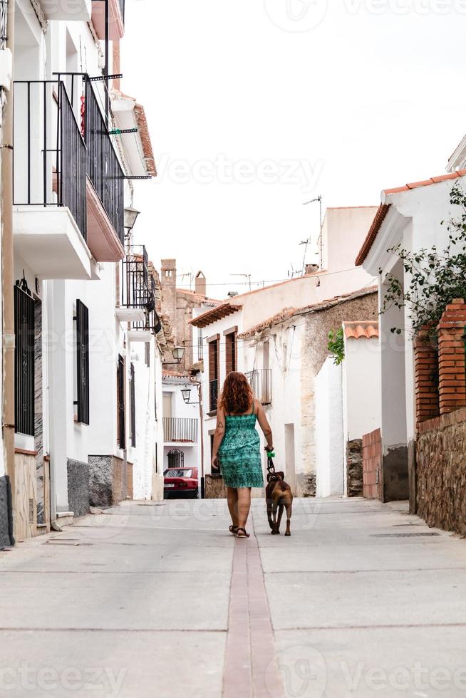 giovane donna che cammina per strada con un cane boxer foto