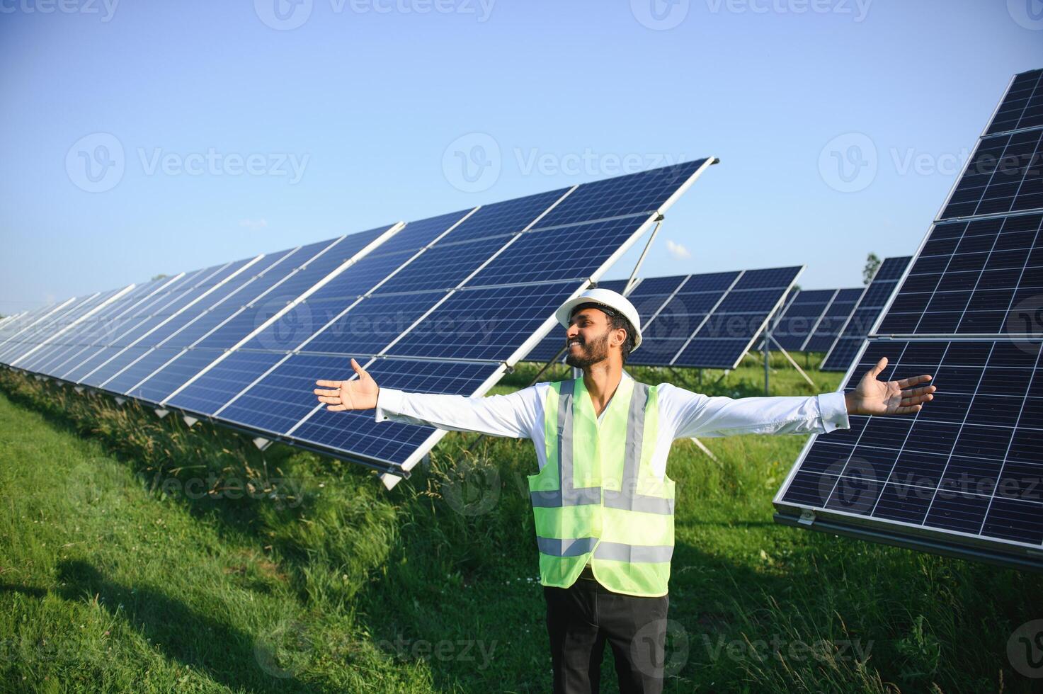 ritratto di giovane indiano maschio ingegnere in piedi vicino solare pannelli, con chiaro blu cielo sfondo, rinnovabile e pulito energia. abilità India, copia spazio. foto