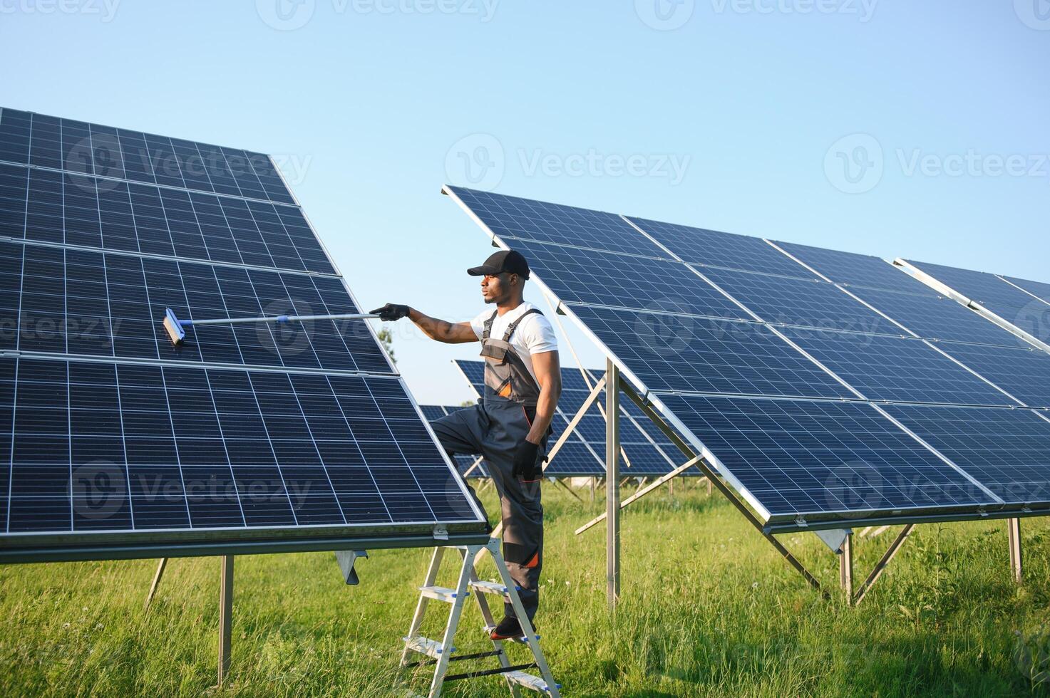 ordinato africano americano lavoratore è pulizia solare pannelli con speciale scopa. foto