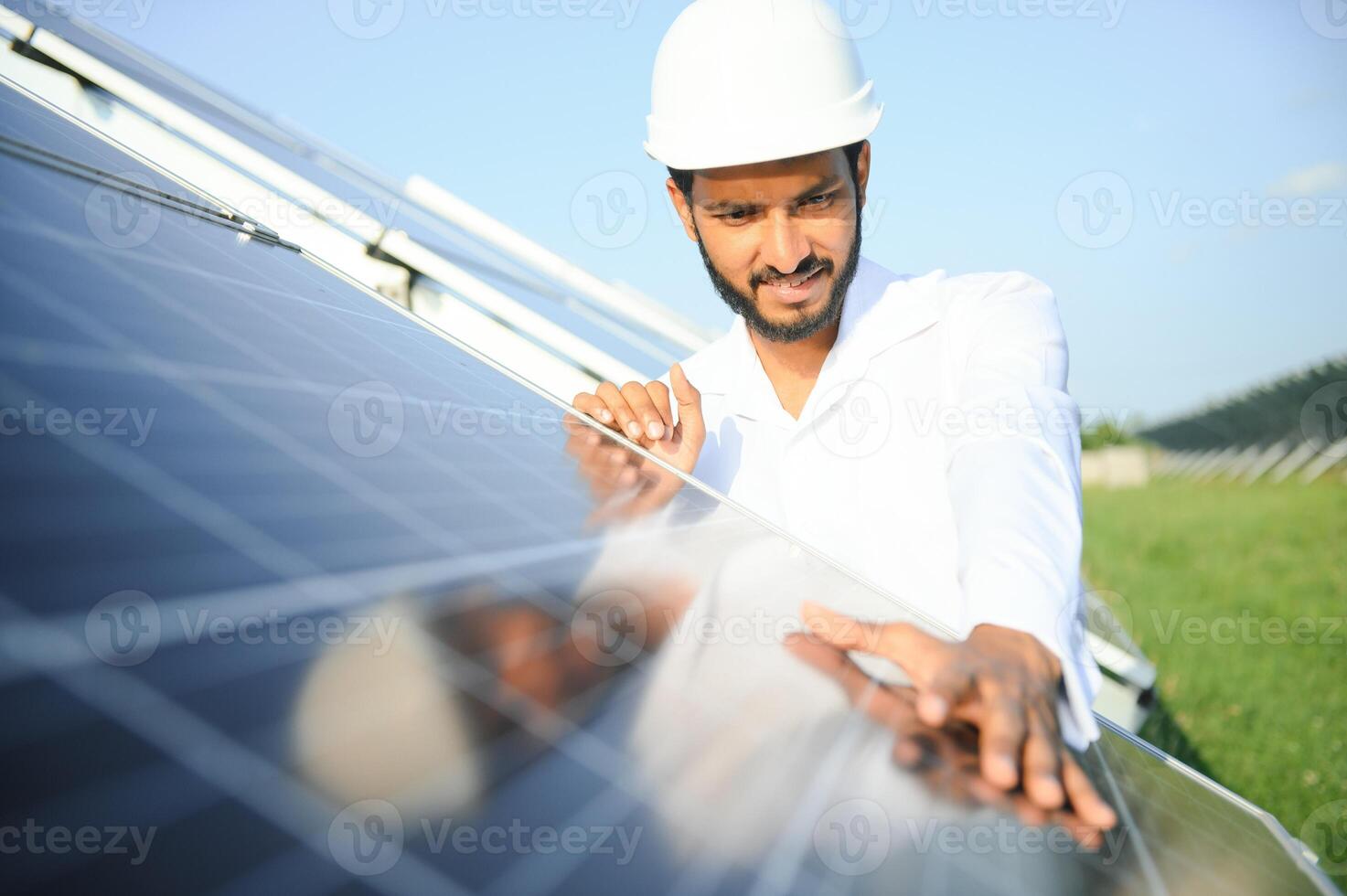 ritratto di giovane indiano maschio ingegnere in piedi vicino solare pannelli, con chiaro blu cielo sfondo, rinnovabile e pulito energia. abilità India, copia spazio. foto