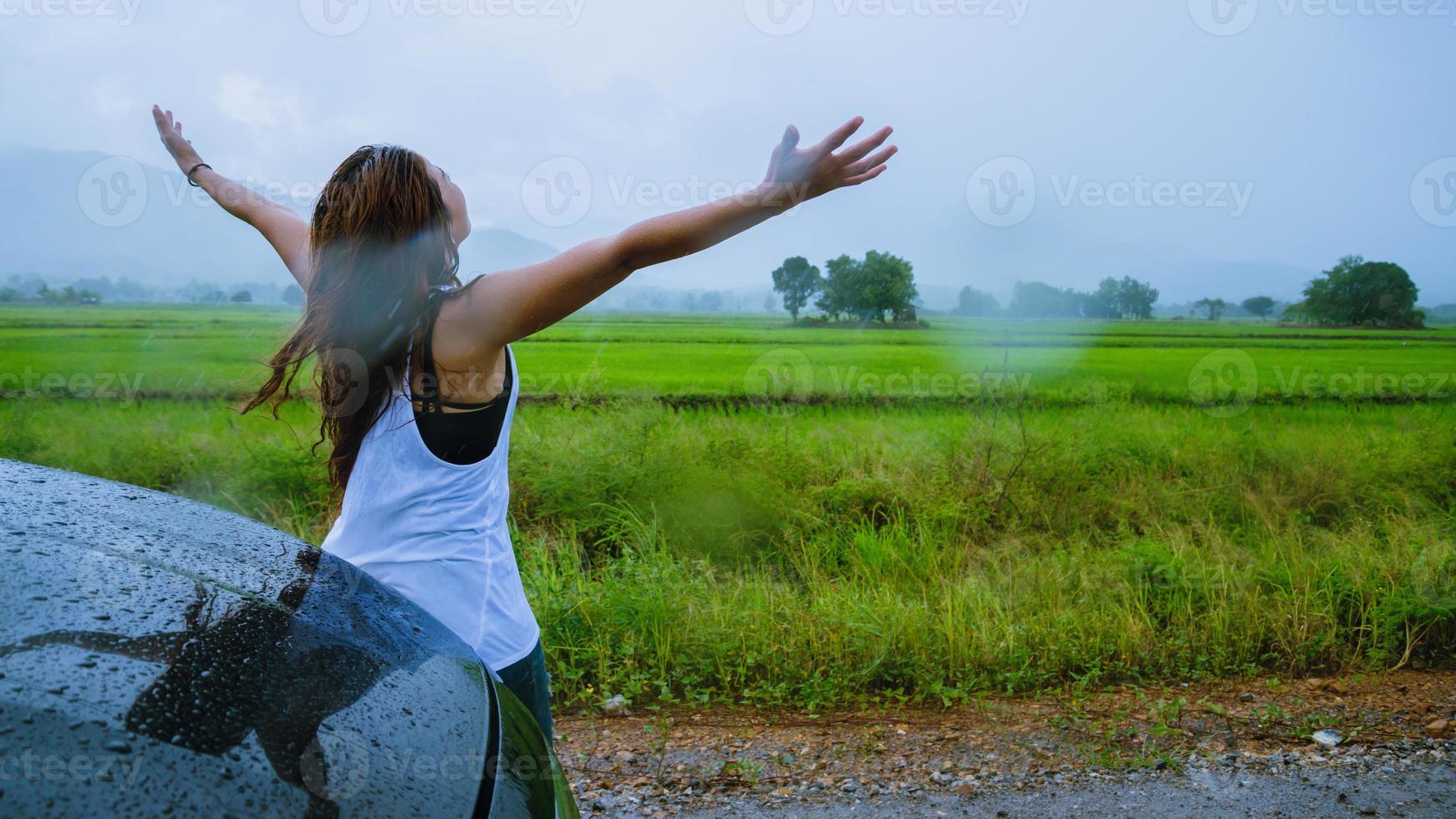 le donne asiatiche viaggiano rilassandosi durante le vacanze. La ragazza sorrise felice e si godette la pioggia che cadeva. turista che viaggia guidando in campagna durante la stagione delle piogge, viaggia in thailandia. foto