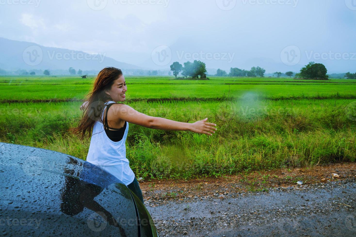 le donne asiatiche viaggiano rilassandosi durante le vacanze. La ragazza sorrise felice e si godette la pioggia che cadeva. turista che viaggia guidando in campagna durante la stagione delle piogge, viaggia in thailandia. foto