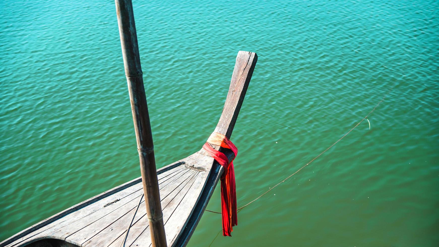 foto della testa della nave di prua con un panno rosso legato. vista dalla testa della tradizionale barca in legno con panno rosso legato. barca da pesca, barca longtail tradizionale thailandese, mare delle andamane.