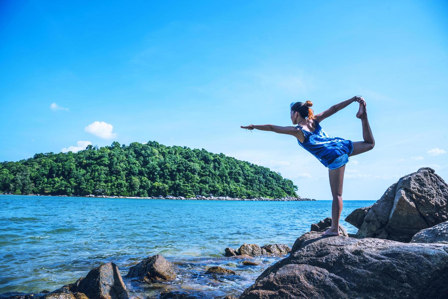 il viaggio della donna asiatica si rilassa durante la vacanza. gioca se lo yoga. sugli scogli in riva al mare. foto
