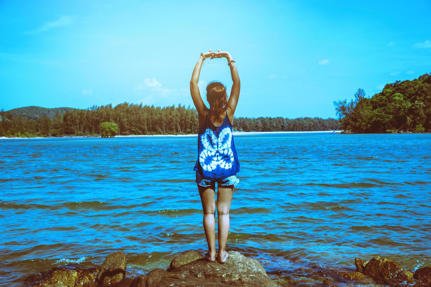 le donne asiatiche si rilassano durante le vacanze. viaggiare rilassati. gioca se lo yoga. sugli scogli in riva al mare. in estate. Tailandia foto