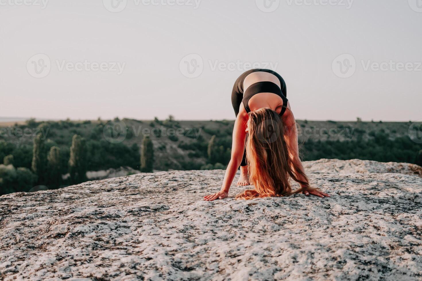 fitness donna. bene guardare mezzo anziano donna con lungo capelli, fitness istruttore nel ghette e cime fare allungamento e pilates su il roccia vicino foresta. femmina fitness yoga routine concetto. foto