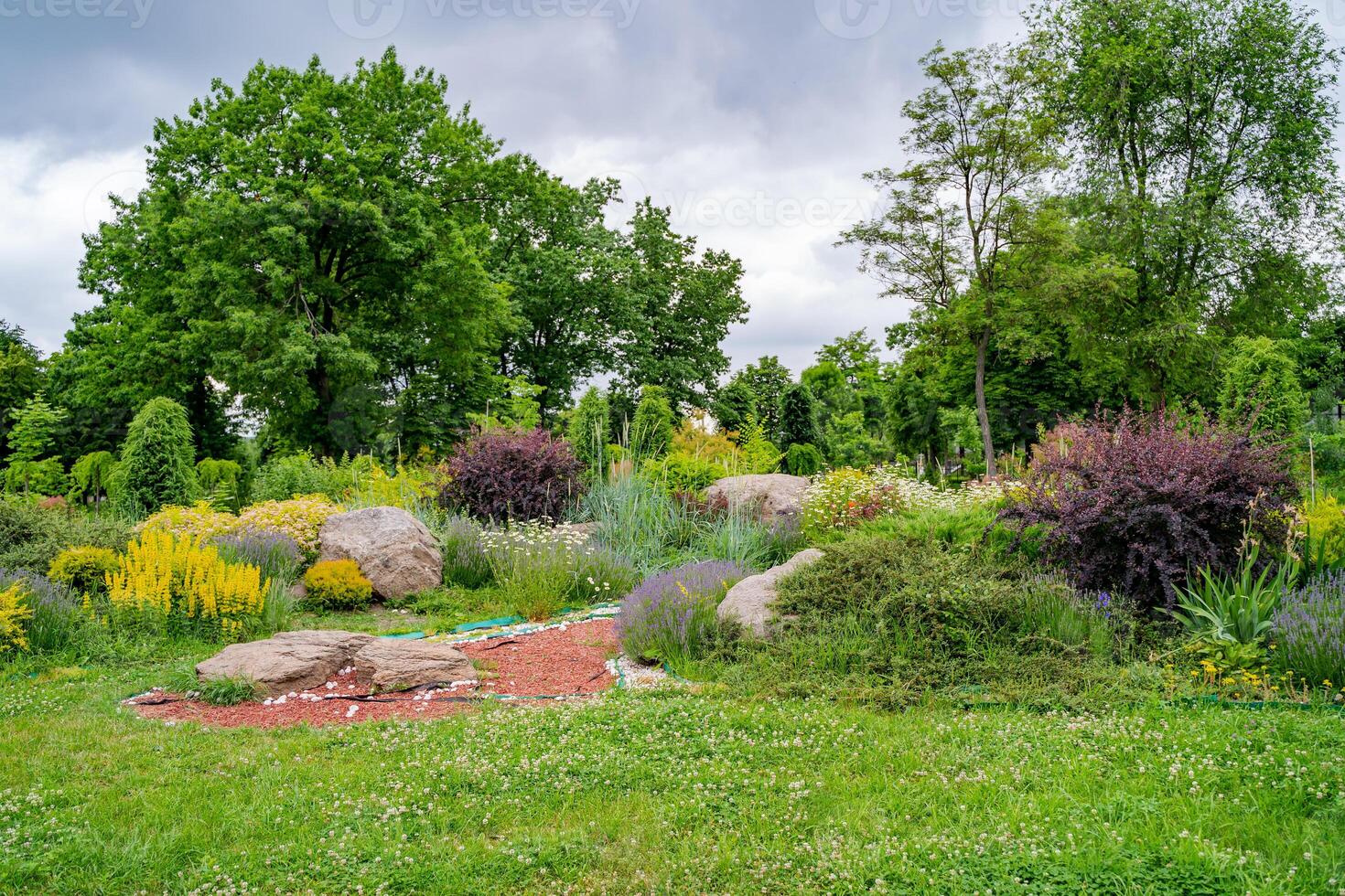 giardinaggio paesaggio e paesaggio design come un' perenne giardino prato con un' letto di fiori e ornamentale impianti nel un' decorativo paesaggistico percorso. foto