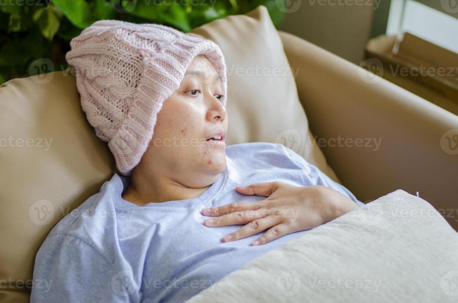 asiatico donna ha cancro, lei è dire bugie su il divano nel il vivente camera. foto