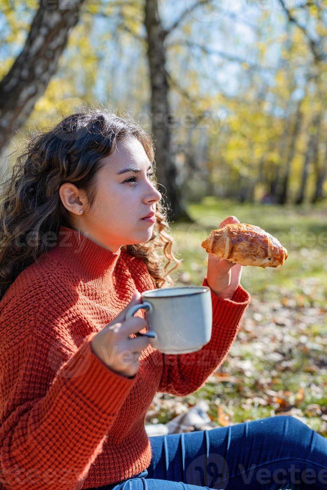 bella donna in maglione rosso durante un picnic in una foresta autunnale foto