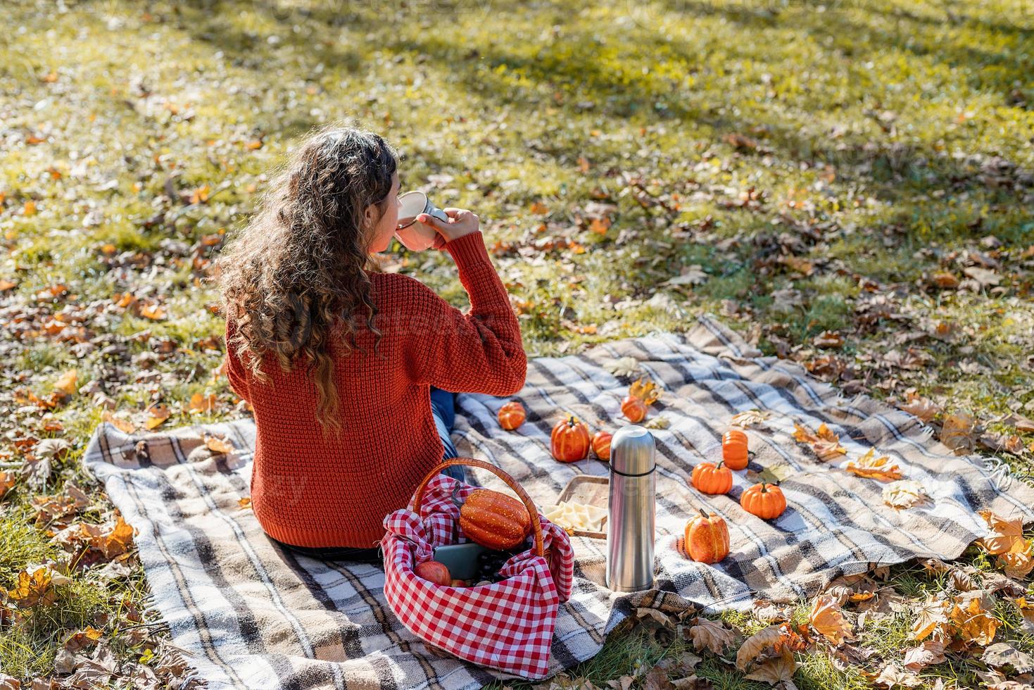 bella donna in maglione rosso durante un picnic in una foresta autunnale foto