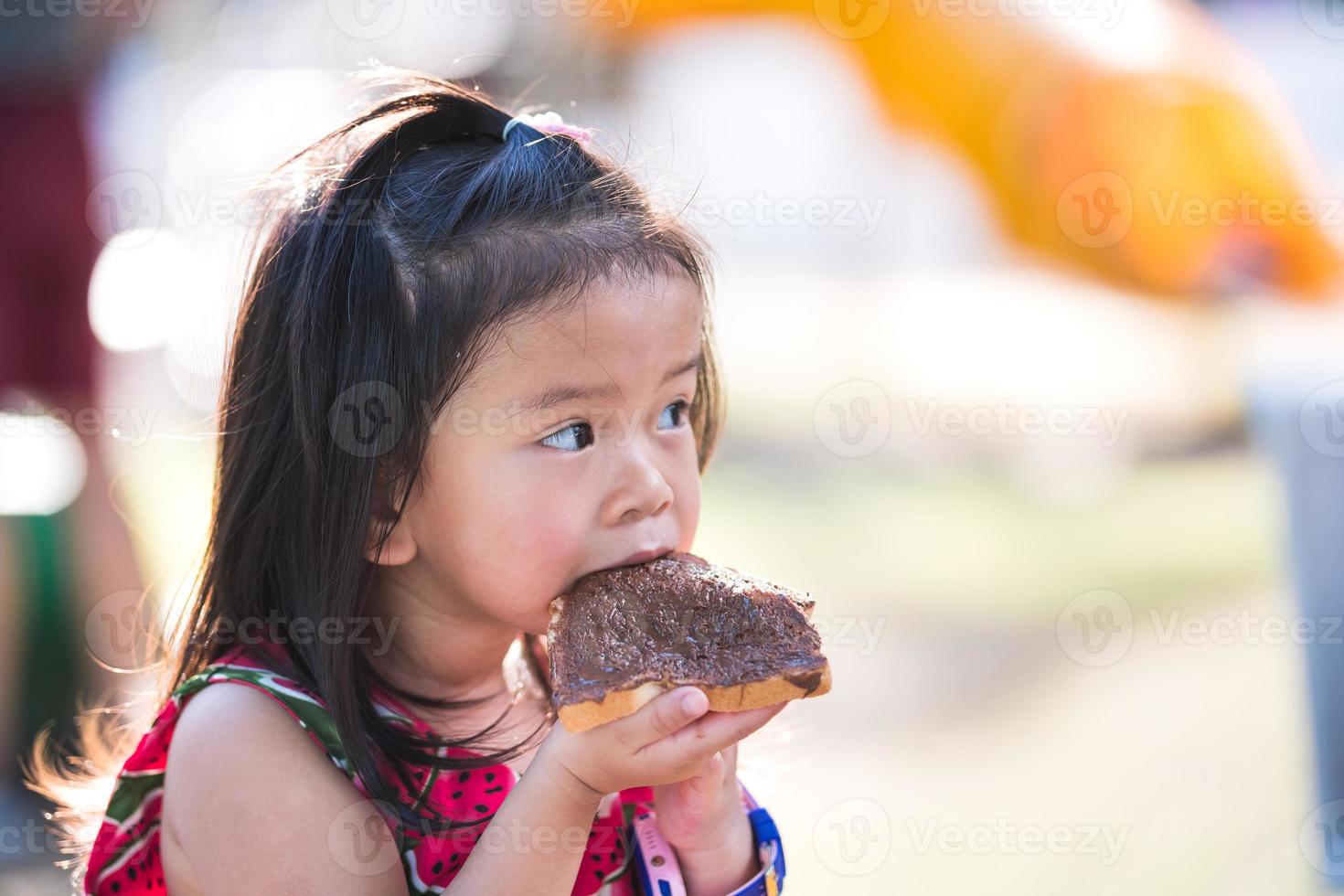 un bambino goloso mangia cioccolato. adorabile ragazzina si diverte a mangiare con uno spuntino da picnic in una vacanza estiva. bambino di 4-5 anni. foto