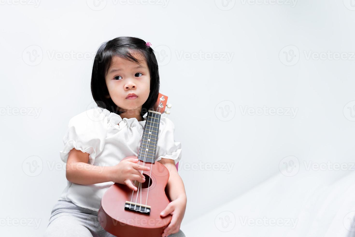 bambina sta suonando l'ukulele. su sfondo bianco. foto