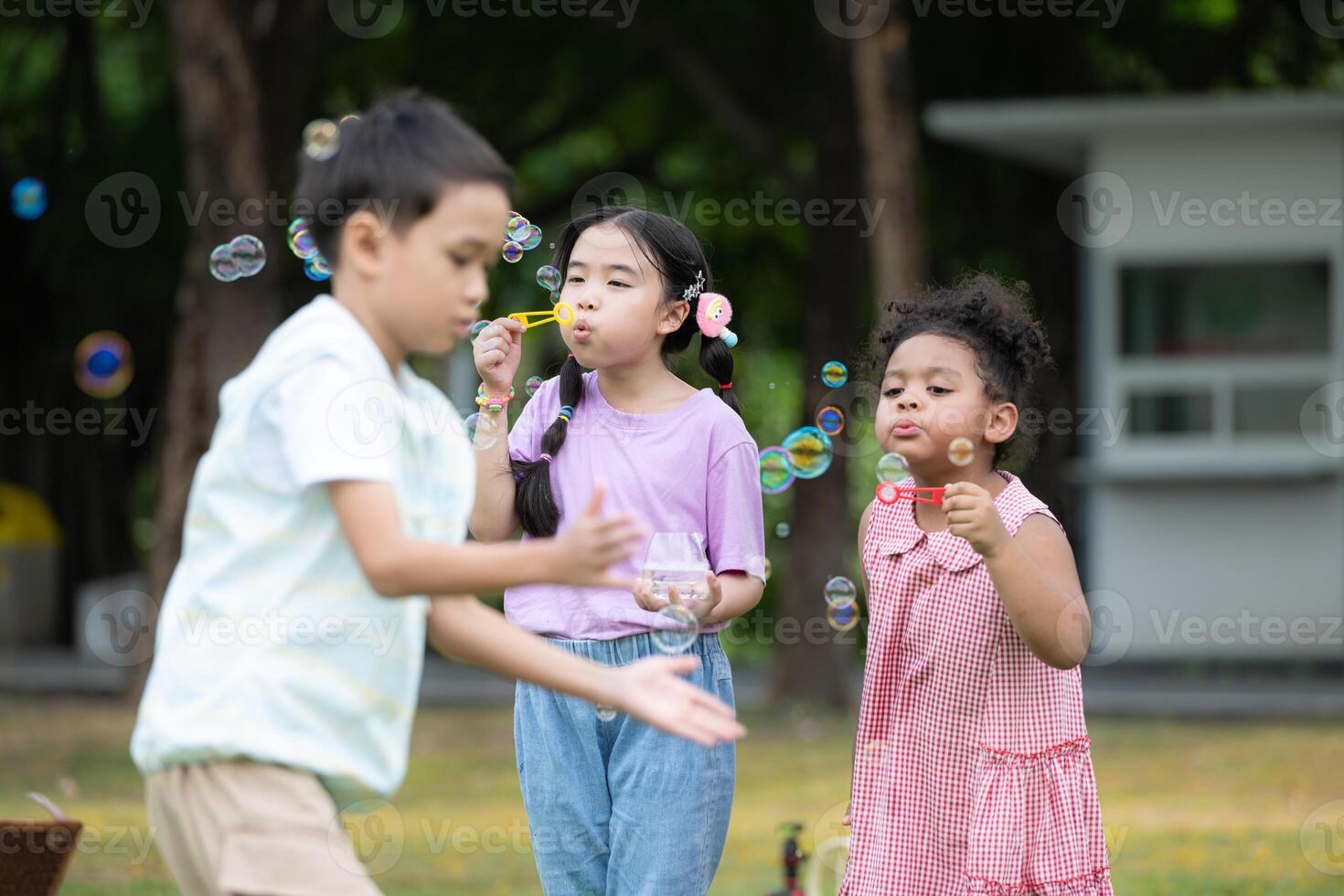 bambini seduta nel il parco con soffiaggio aria bolla, circondato di verdura e natura foto