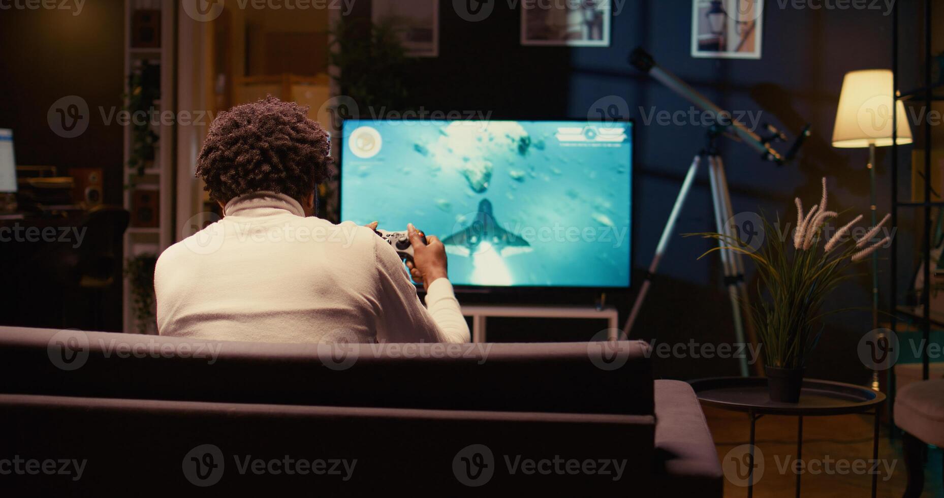 uomo nel casa Teatro utilizzando nube gioco servizio per giocare esigente scienza finzione video gioco su tv. gamer godendo alto qualità grafica, streaming gioco al di sopra di il Internet, panning tiro foto