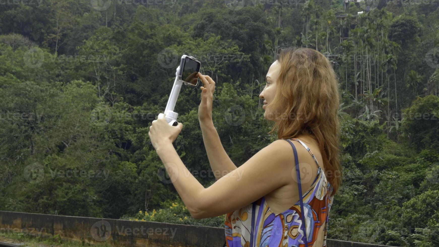 bellissimo donna prende immagini su Telefono con treppiedi. azione. donna professionalmente spara paesaggi su Telefono mentre in viaggio per blog. tiro per viaggio blog foto