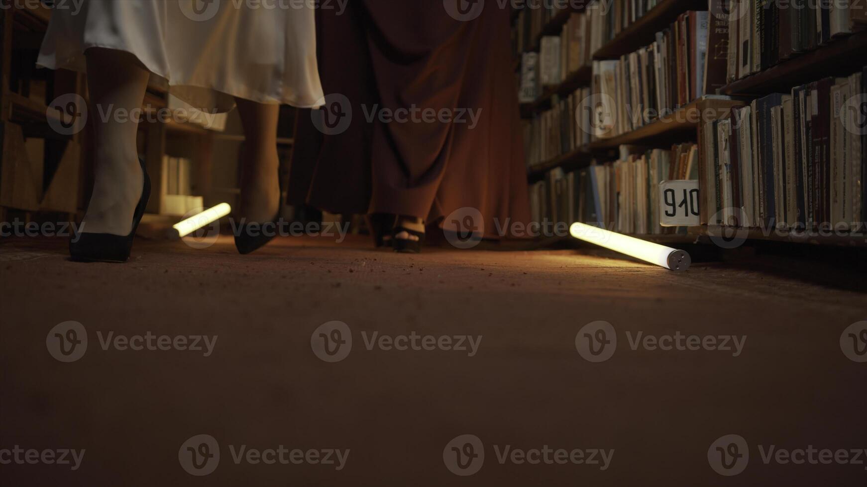 donne siamo misteriosamente a piedi nel biblioteca. azione filmato. segreto sorority nel notte biblioteca. elegante donne misteriosamente raccogliere nel notte biblioteca con lampeggiante leggero foto