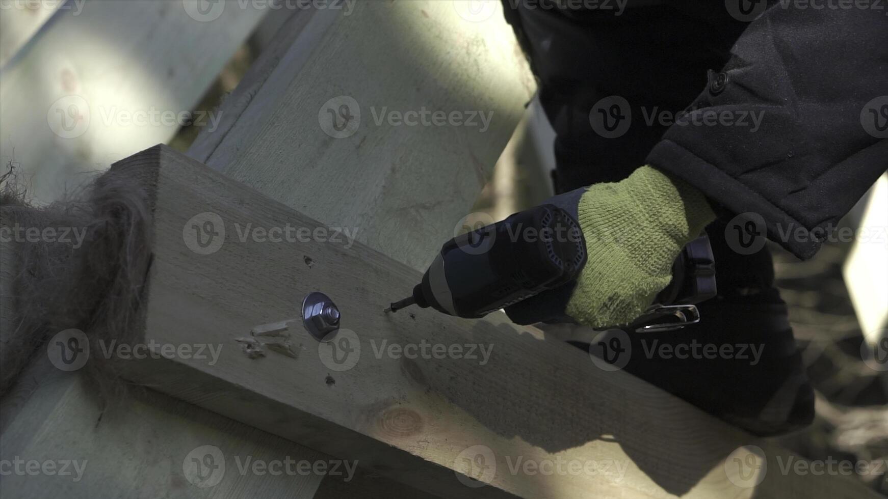 avvicinamento di costruttore perforazione di legno struttura. clip. uomo trapani di legno travi di Casa sotto costruzione. costruzione di di legno nazione Casa foto