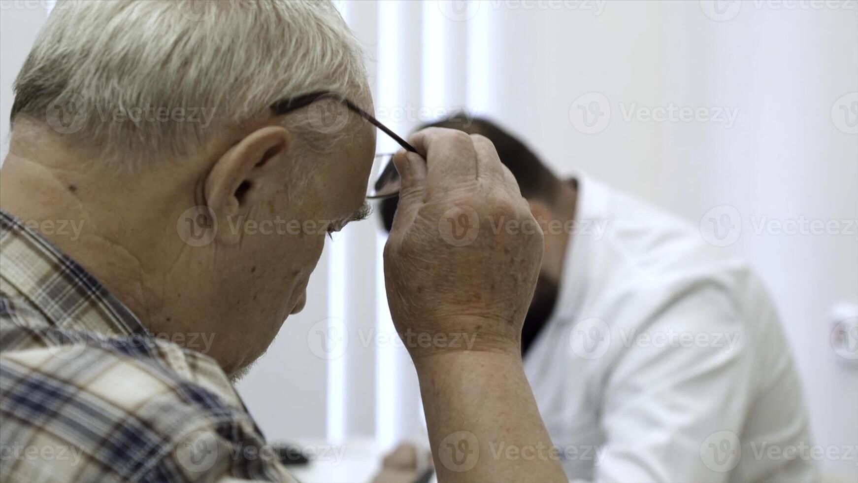 maschio medico Lavorando a il tavolo, scrittura prescrizione. clip. vecchio maschio paziente a il Ospedale. foto