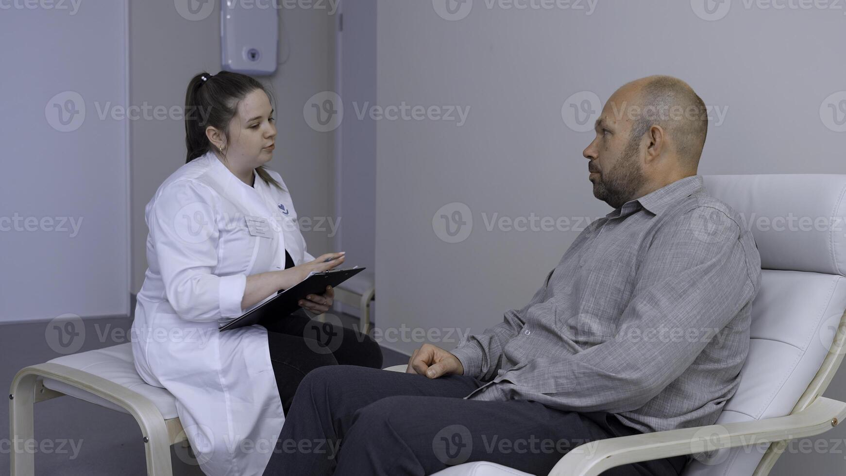 medico Lavorando nel il ufficio e dando raccomandazioni per il paziente. clip. giovane femmina medico spiegando sintomi per maschio paziente, Salute cura e assistenza concetto. foto