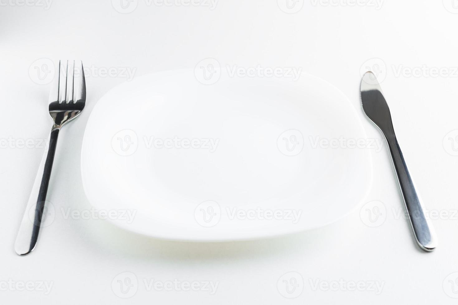 piatto vuoto, forchetta e coltello su sfondo bianco foto