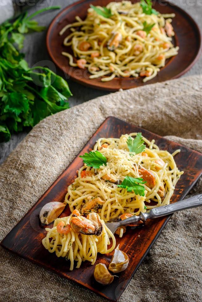 pasta italiana in salsa cremosa con frutti di mare, gamberi e cozze alla piastra foto