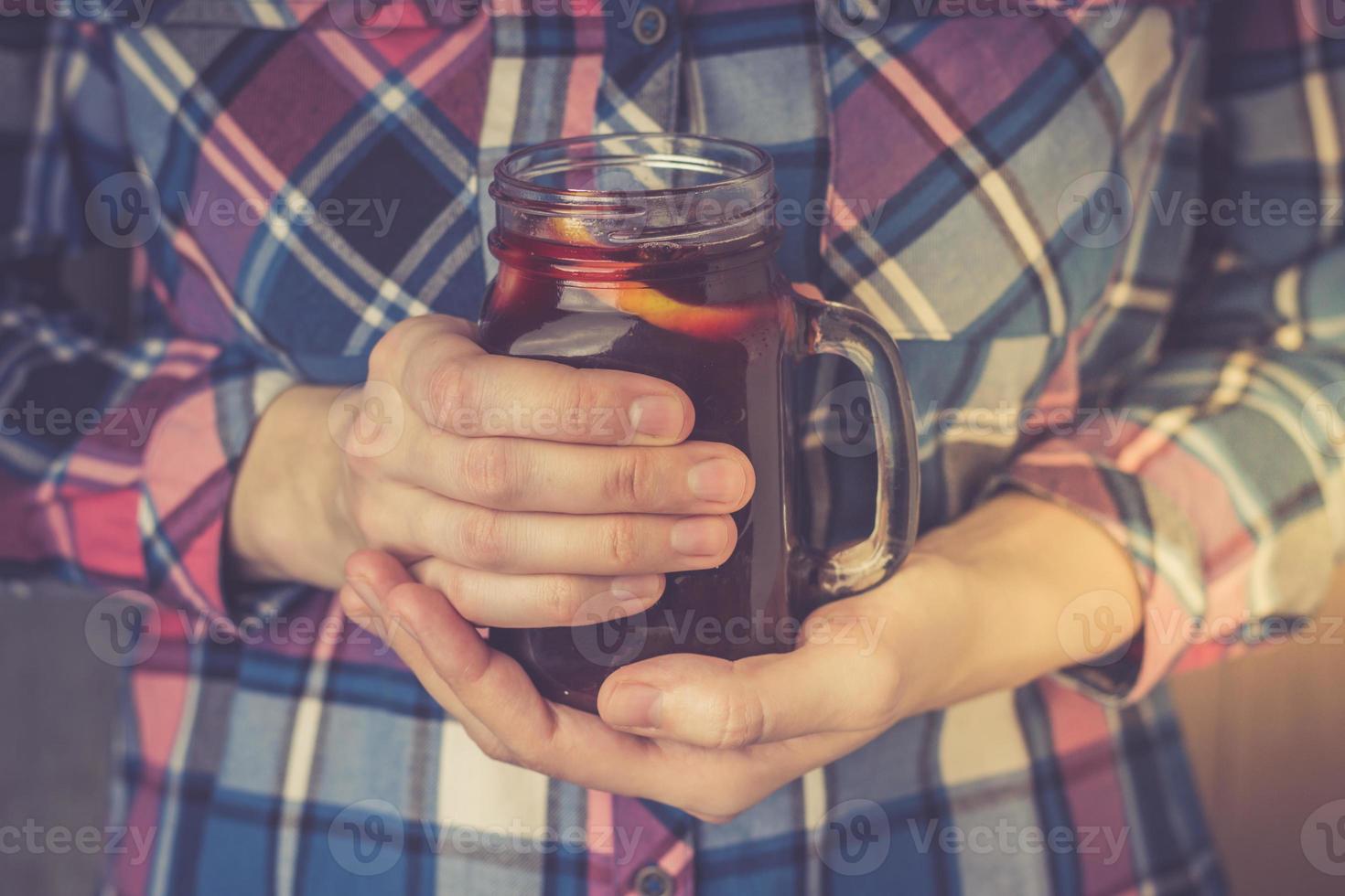 una giovane donna in camicia tiene in mano una tazza di vin brulé fatto in casa. foto