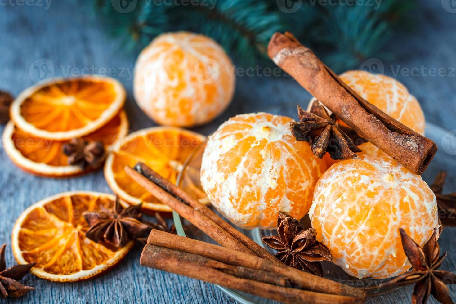mandarini, arance essiccate, anice e bastoncini di cannella su un tavolo di legno accanto al ramo di abete foto