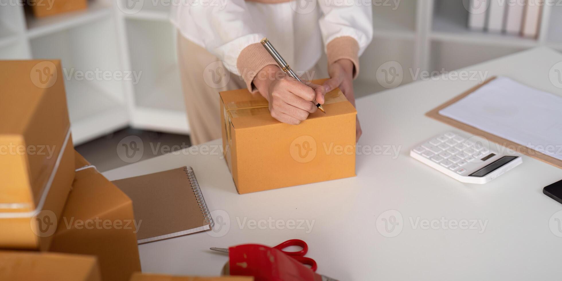 donna è scrittura un' elenco di cliente su carta prima spedizione per loro, lei corre un e-commerce attività commerciale su siti web e sociale media. concetto di vendita prodotti in linea foto