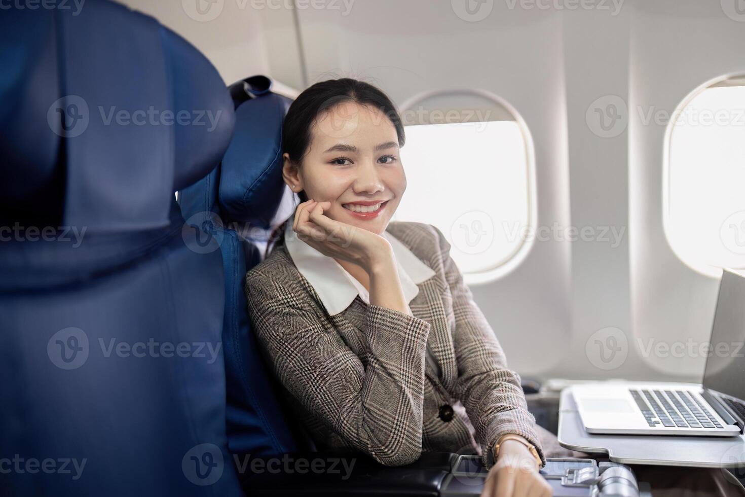 un' donna d'affari è seduta su aereo posto a sedere con un' Sorridi su sua viso foto