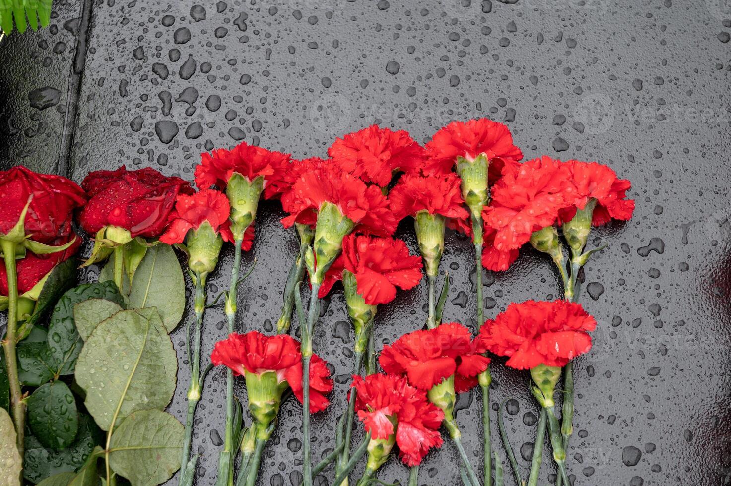 rosso garofano fiori e Rose siamo di cui su un' marmo lastra nel il pioggia foto