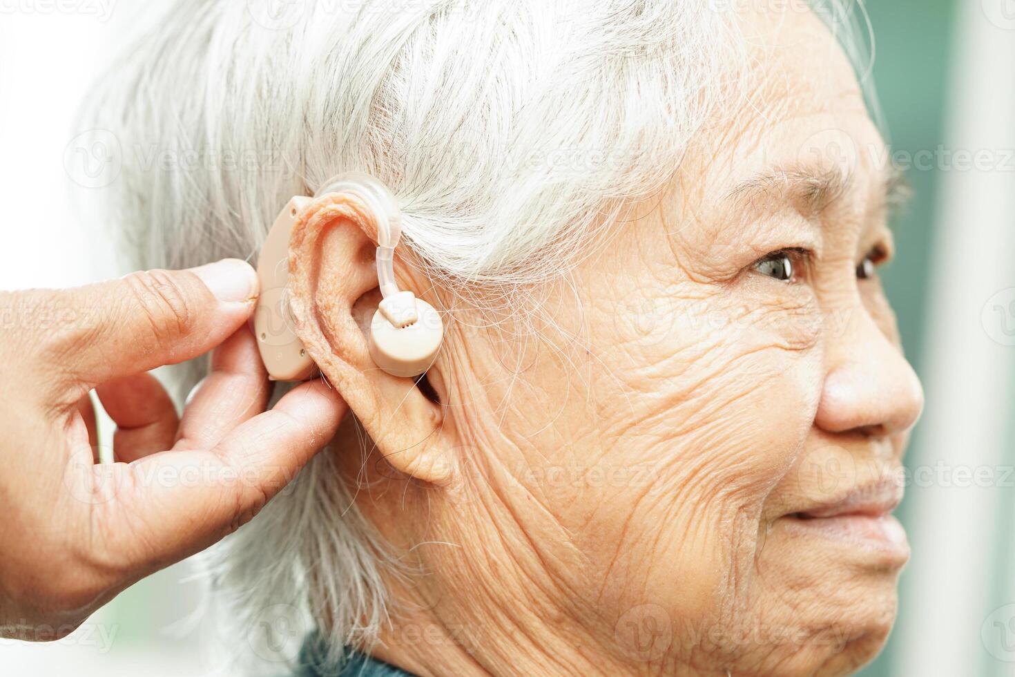 medico installare udito aiuto su anziano paziente orecchio per ridurre udito perdita problema. foto