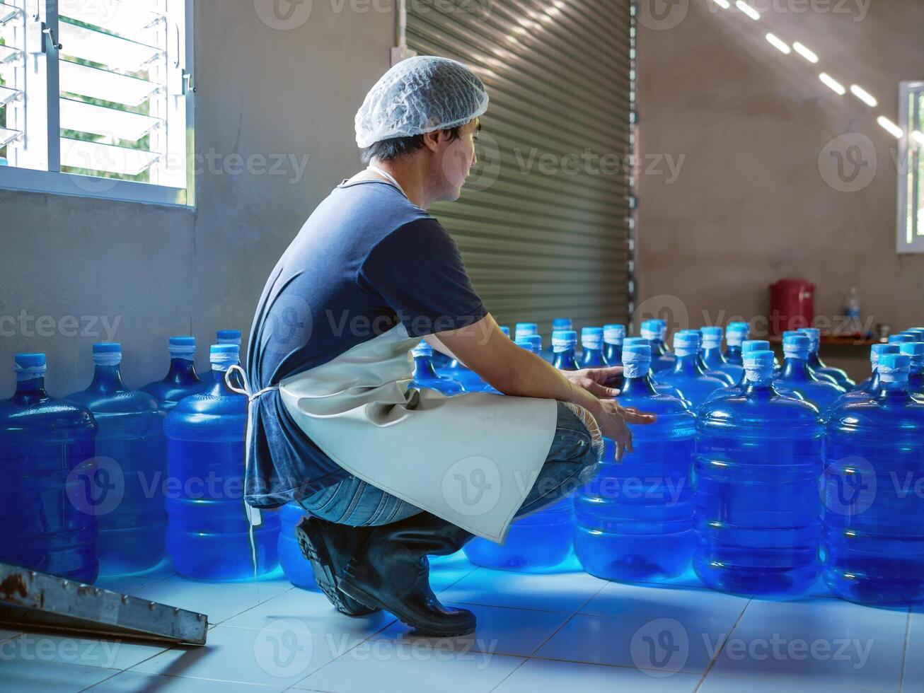 asiatico uomo lavoratore o qualità ispettore nel abbigliamento da lavoro Lavorando nel controllo potabile acqua blu gallone nel bevanda acqua fabbrica prima spedizione.bere acqua affari,piccolo affari, negozio, magazzino foto