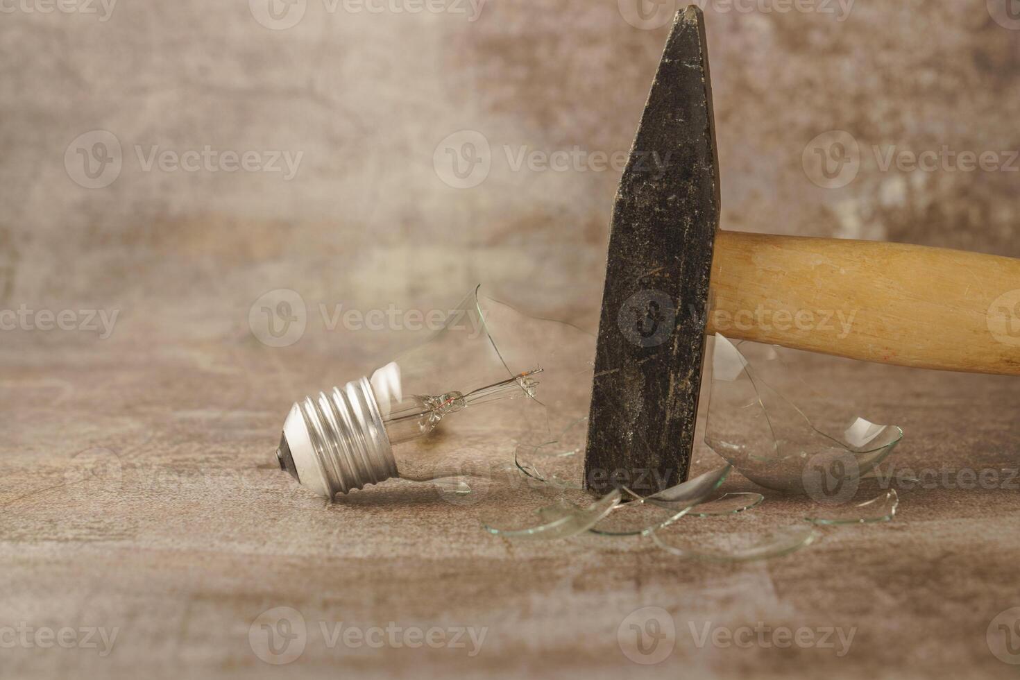 martello rottura un' leggero lampadina su un' calcestruzzo pavimento foto