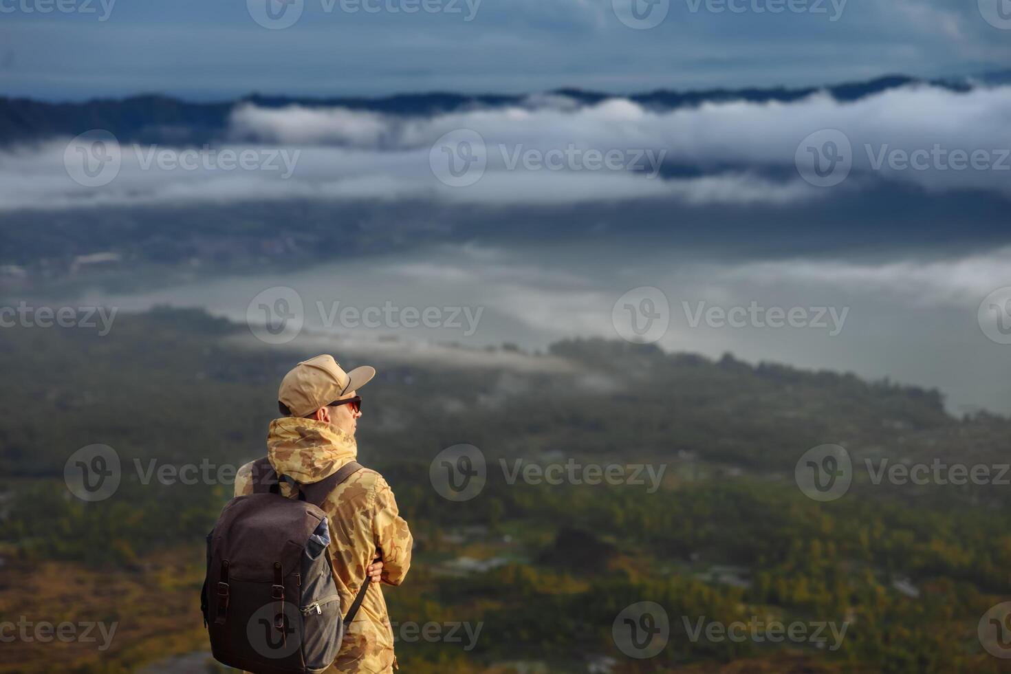 uomo turista sembra a il Alba su il vulcano batur su il isola di blai nel Indonesia. escursionista uomo con zaino viaggio su superiore vulcano, viaggio concetto foto