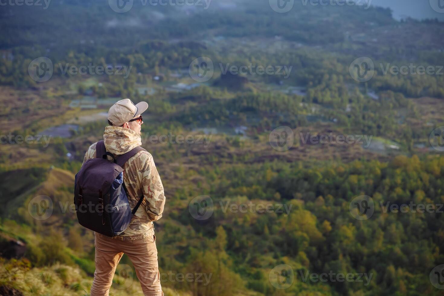 uomo turista sembra a il Alba su il vulcano batur su il isola di blai nel Indonesia. escursionista uomo con zaino viaggio su superiore vulcano, viaggio concetto foto