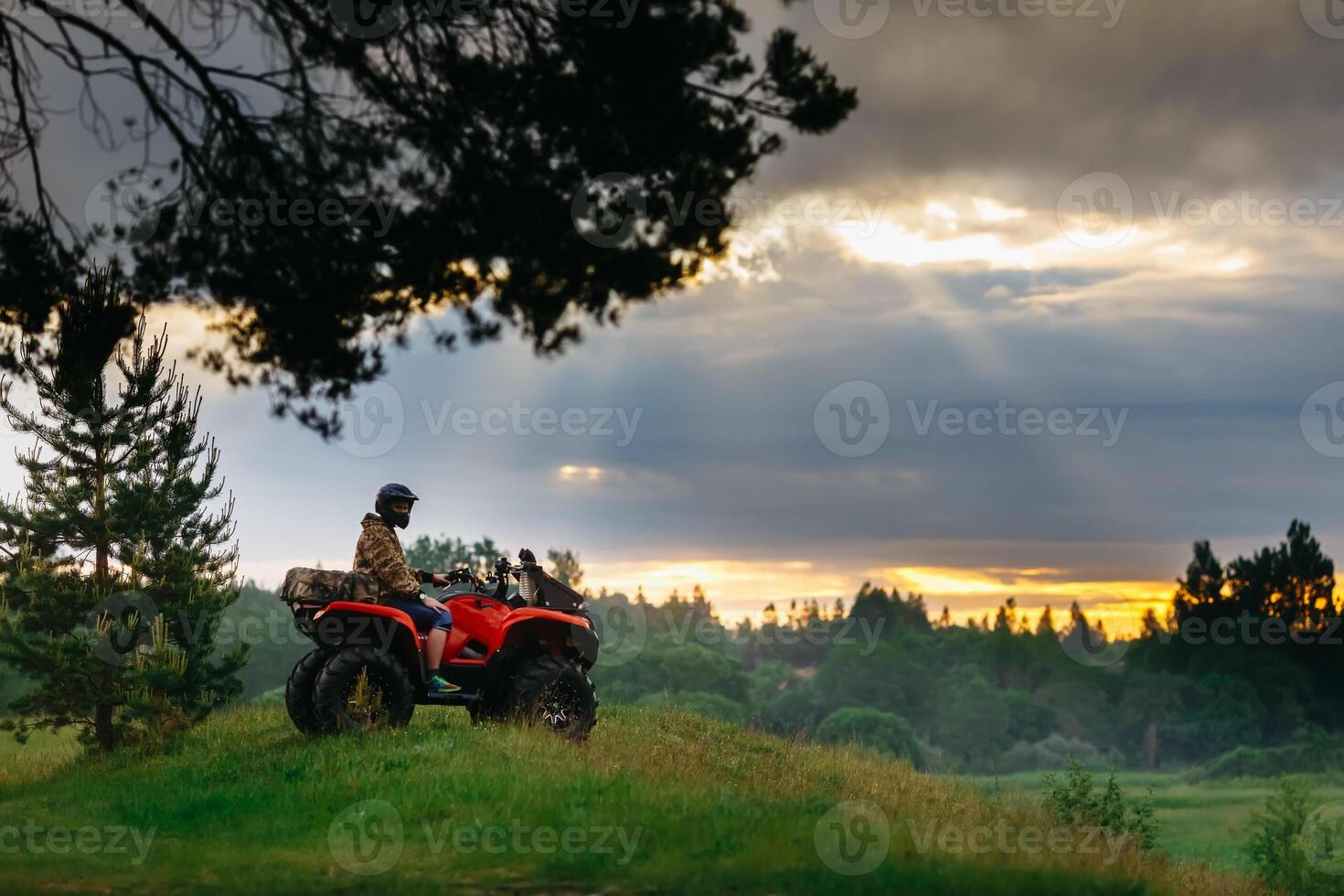 uomo su il atv quadrilatero bicicletta in esecuzione a tramonto foto