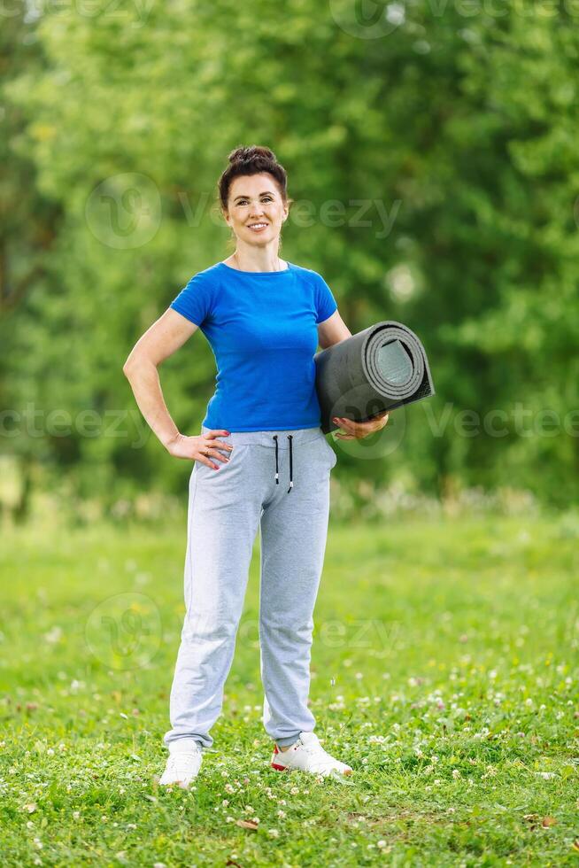 portret di anziano donna esercizio nel parco. anziano femmina fare fitness esercizi all'aperto. sano vita stile concetto. copyspace. foto