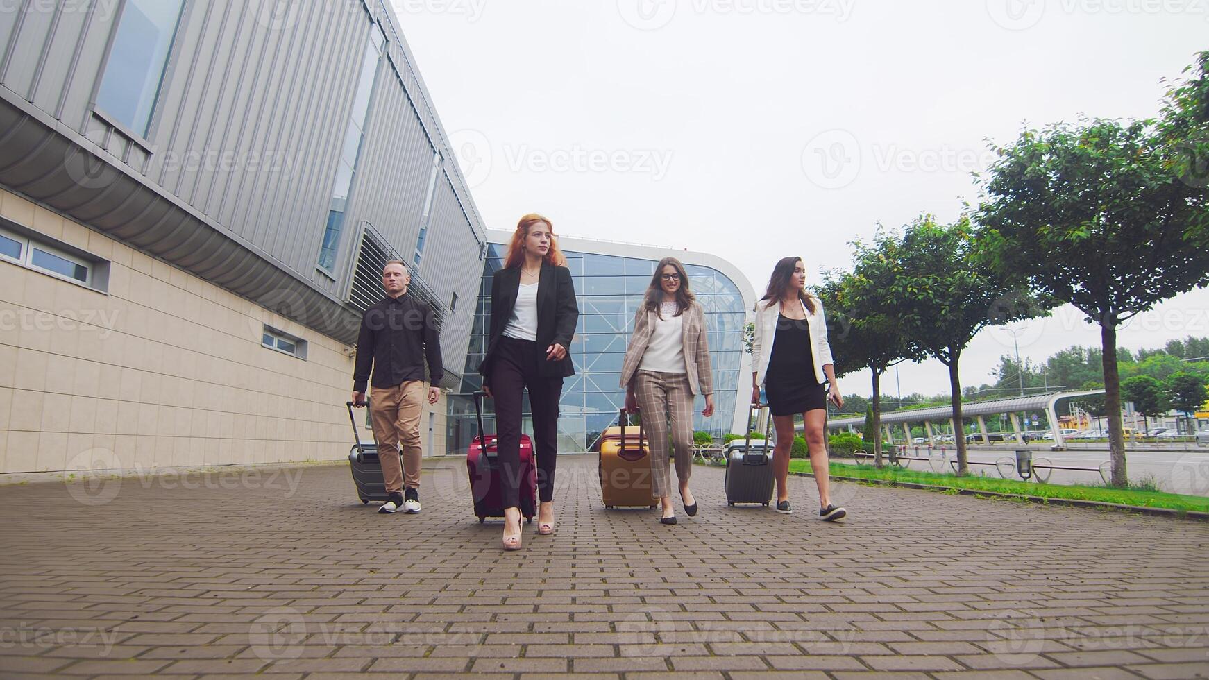 gruppo di turisti a piedi con bagaglio su il sfondo di il aeroporto terminale. un' gruppo di giovane uomini d'affari con bagaglio volò per un' nuovo città e camminare contro il fondale di un' nuovo moderno aeroporto foto