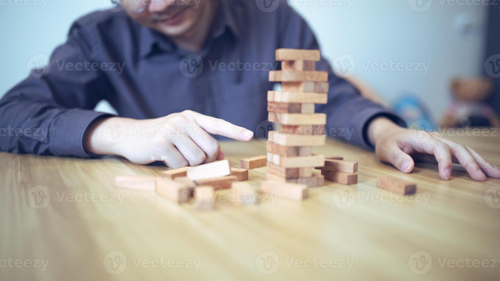 attività commerciale strategia concetto con mani giocando un' di legno bloccare Torre gioco, simboleggiante rischio e stabilità. pianificazione rischio gestione foto