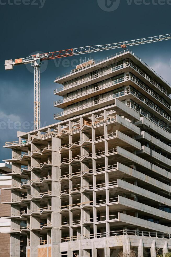 Torre gru sopra un appartamento edificio sotto costruzione contro un' tempestoso cielo foto