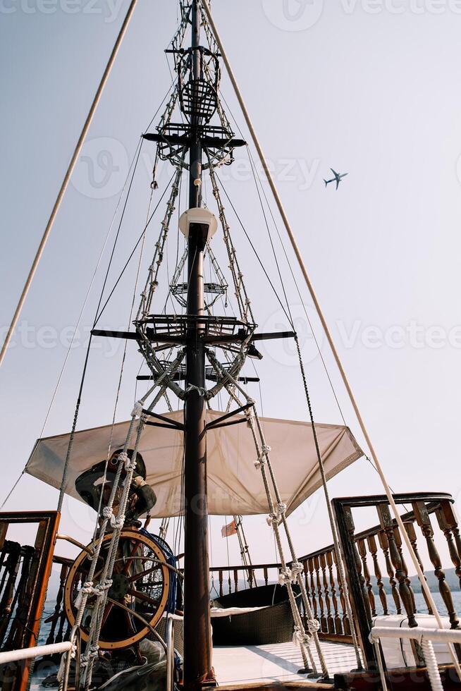 Capitano a il timone di un' di legno goletta andare in barca su il mare contro il fondale di un aereo volante nel il cielo foto